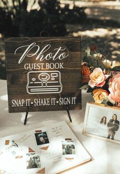 a wooden sign sitting on top of a table next to pictures and flowers in vases