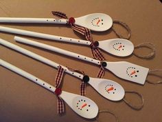 four snowman spoons tied with twine on a brown tablecloth covered surface