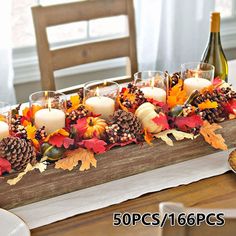 a wooden table topped with candles and fall leaves