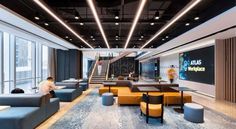 an office lobby with couches, tables and stairs leading up to the second floor