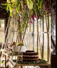 a wedding cake sitting on top of a wooden table next to flowers and greenery