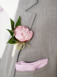 a man in a gray suit with a pink boutonniere on his lapel