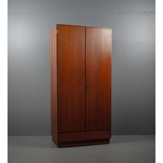 a tall wooden cabinet sitting on top of a white floor next to a gray wall