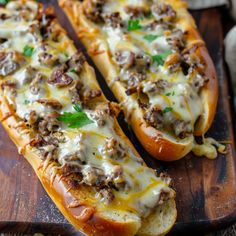 two hot dogs with cheese and meat on a cutting board