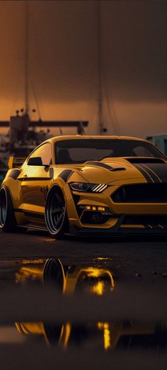 a yellow sports car parked in front of a boat at night with the lights on