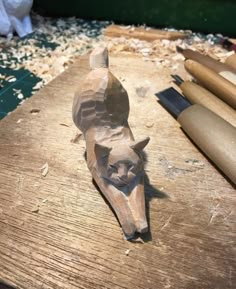 a wooden carving of a cat sitting on top of a table next to some wood shavings