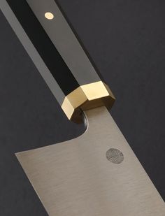 a knife with a gold handle on a black surface and the blade has a fingerprint