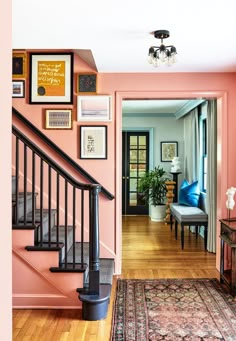 a living room with pink walls and pictures on the wall above the stair railings