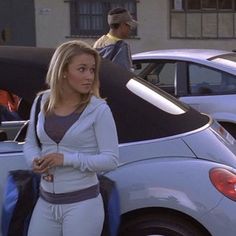 a woman standing next to a parked car