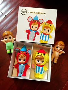 three little toy figurines in a box on a wooden floor next to each other