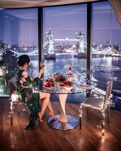 a woman sitting at a table in front of a large window overlooking the city skyline