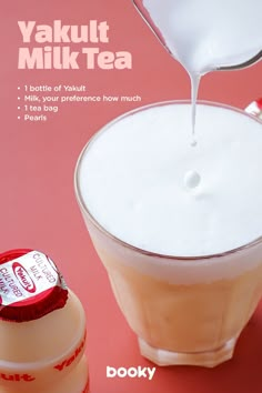 a bottle of yogurt being poured into a glass cup with milk in it