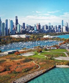 an aerial view of a city with boats in the water and fall foliage around it