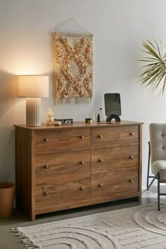 a room with a large wooden dresser next to a chair and lamp on the floor