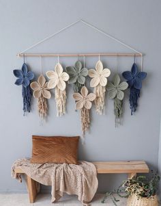 a wooden bench sitting next to a wall hanging with crocheted flowers on it