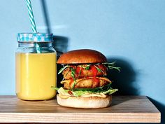 a sandwich and drink sitting on top of a wooden table next to a blue wall