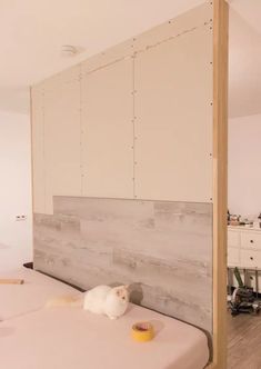 a white cat laying on top of a bed next to a wooden headboard and dresser