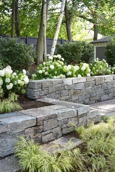 a stone wall with white flowers in the middle