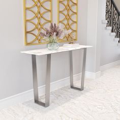 a vase with flowers sitting on top of a white table next to a stair case