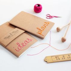 two notebooks with writing on them next to a measuring tape and some yarn, scissors