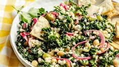 a bowl filled with salad and tortilla chips on top of a table cloth