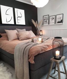 a bed sitting in a bedroom next to a night stand with candles and pictures on the wall