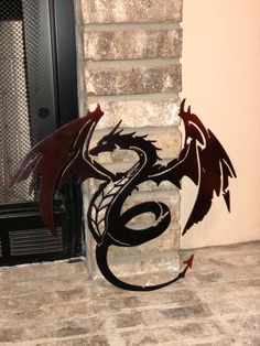 a metal dragon sculpture sitting on top of a tile floor next to a fireplace door