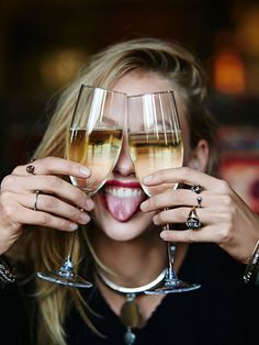 a woman holding two wine glasses up to her face