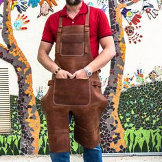 a man in overalls and a red shirt is holding a brown leather tool bag