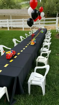 a long table set up with balloons and cars for a race car themed birthday party