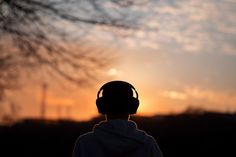 the silhouette of a person wearing headphones at sunset