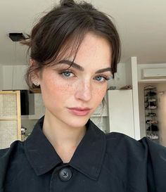 a woman with freckled hair and blue eyes wearing a black shirt looking at the camera