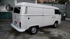 an old white van parked in front of a building next to a man standing on the sidewalk