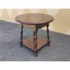 a small wooden table sitting on top of a cement floor next to a yellow wall