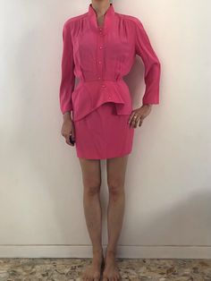 Wow! Amazing Thierry Mugler hot pink suit set.  Very cute Barbie energy! The suit is made amazingly, like all Mugler pieces. Super stitching and construction - couture quality.  The fabric is a heavy rayon and acetate with a shiny satin interior. It has a great heavy weight with a wonderful drape.  The jacket has a 1940's style.  Kimono sleeves with gathers at the shoulders.  The neckline is deep and open with a band collar.  Pink plastic snaps up the front.  Asymmetrical reinforced peplum! Also one cool Mugler pocket on the peplum.  Mini skirt has a high waist and a fitted shape.  Pink plastic snaps up the back.  Waist band with V detail.  Both pieces are unlined. The fabric is satin on the inside.  Label Thierry Mugler Paris, Skirt has the size 38, 67% acetate, 33% viscose. Dry Clean onl Chic Pink Long Sleeve Sets, Chic Fitted Pink Sets, Pink Long Sleeve Skirt Suit For Spring, Fitted Pink Sets For Workwear, Spring Pink Skirt Suit For Party, Spring Pink Long Sleeve Skirt Suit, Chic Pink Party Skirt Suit, Chic Pink Skirt Suit For Party, Chic Pink Skirt Suit For Formal Events