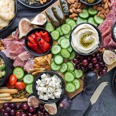 an assortment of food is laid out on a table with cheese, crackers, tomatoes, cucumbers and other foods