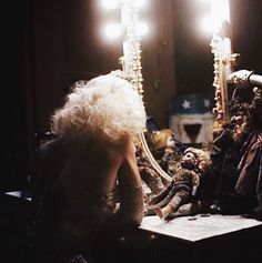 a woman sitting at a table in front of a mirror with candles on top of it