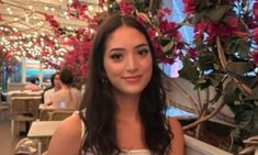 a woman sitting at a table with flowers in the background