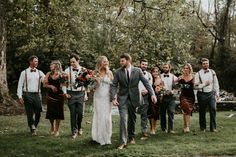 a bride and groom walking with their bridal party in the background at this rustic wedding