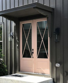 a pink double door on the side of a metal building with black trim and windows