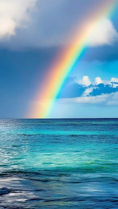 a rainbow shines in the sky over the ocean