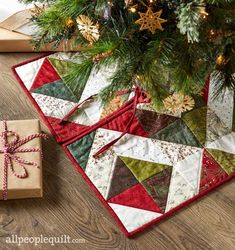 a christmas tree with presents under it on the floor next to a small gift box