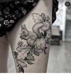 a woman's thigh with a squirrel and flowers tattoo on her leg, which is black and white