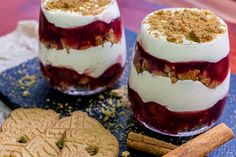 two desserts on a blue plate with cookies and cinnamon sticks next to them,