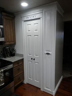 a kitchen with white painted doors and wooden cabinets