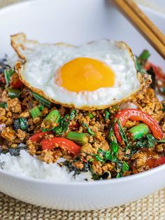 an egg on top of rice in a bowl with chopsticks