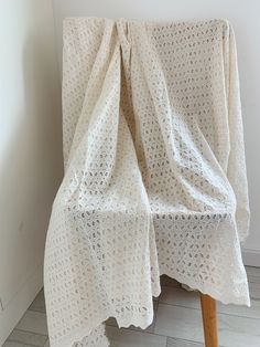 a white crocheted blanket draped over a wooden chair