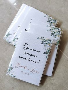 two wedding cards with the names of their guests and date printed on them, sitting on a tile floor