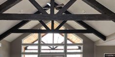 a living room filled with furniture and a large window covered in wood beams on the ceiling