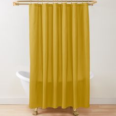 a yellow shower curtain in a bathroom with wood flooring and white bathtub next to it